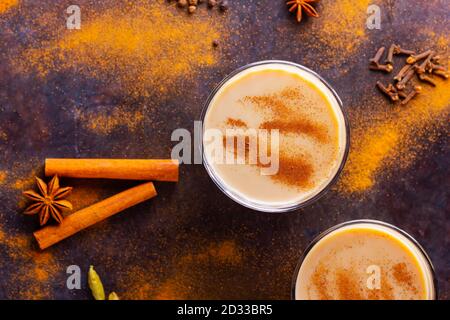 Masala Chai Tee auf schwarzem Hintergrund. Zwei transparente Gläser Masala-Tee und verschiedene Gewürze verstreut. Draufsicht Stockfoto