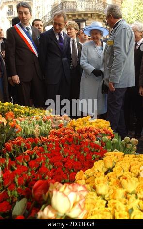 Die britische Königin Elizabeth II. Während ihres offiziellen Staatsbesuchs in Paris, während sie bei einem örtlichen Floristen vor dem Cerise Community Center Blumenschüsseln sieht. Früher heute säumten Hunderte von Menschen die gepflasterten Bürgersteige der Straße, um die Königin zu sehen, standen auf ihren Balkonen und winkten, als sie zwischen den Restaurants und Geschäften hinunterging. Stockfoto