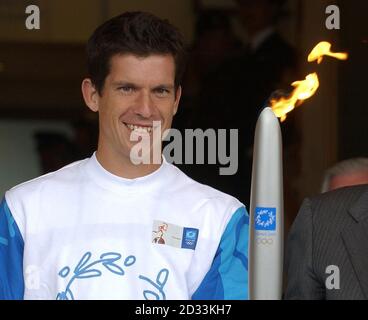 Tim Henman hält die olympische Fackel, nachdem er sie von Sir Roger Bannister vor dem Center Court bei den Lawn Tennis Championships in Wimbledon erhalten hat. Henman übergab die Flamme später an die ehemalige Meisterin Virginia Wade für die Reise nach Zentral-London. Stockfoto