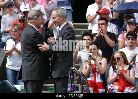 Der ehemalige Champion John McEnroe und Turnierschiedsrichter Alan Mills auf dem Center Court im All England Lawn Tennis Club in Wimbledon, London, wo Tennis am mittleren Sonntag der Lawn Tennis Championships zum dritten Mal in der Geschichte des Turniers gespielt wurde, weil zwei Tage verlassene Spiel durch Regen in der ersten Woche der vierzehn Tage verursacht wurde. Wegen der ermäßigten Eintrittspreise wird er als "Volkssonntag" bezeichnet. NUR FÜR REDAKTIONELLE ZWECKE, KEINE VERWENDUNG VON MOBILTELEFONEN. Stockfoto