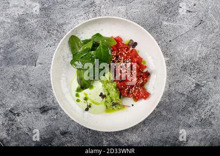 Exquisites Thunfischfilet mit rohem Fischtartar und grünem Gemüse aus nächster Nähe Auf einem weißen Teller Stockfoto