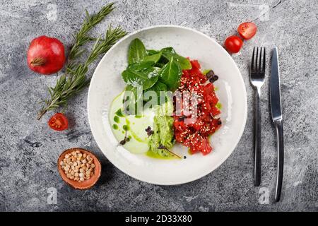 Exquisites Thunfischfilet mit rohem Fischtartar und grünem Gemüse aus nächster Nähe Auf einem weißen Teller Stockfoto