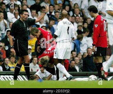 Manchester United Kapitän David Beckham wirft einen Blick auf Leeds United's Lee Bowyer (unten), nachdem er ihm den Ellbogen zu geben schien, wobei Schiedsrichter Jeff Winter (links) während des FA Barclaycard Premiership Spiels auf dem LEED's Elland Road Ground auf den Vorfall zuging. Leeds United besiegte Manchester United mit 1:0. Stockfoto