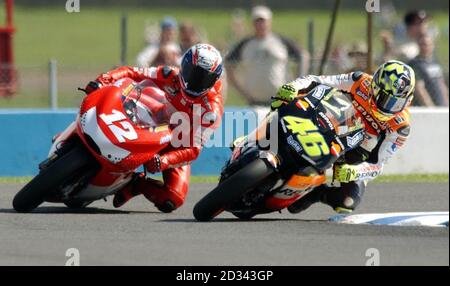 Italien und Repsol Honda Fahrer Valentino Rossi (46) und Australien und Ducati Marlboro Team Troy Bayliss (12) während MotoGP freies Training beim Cinzano British Grand Prix, Donington Park, Leicestershire. Stockfoto