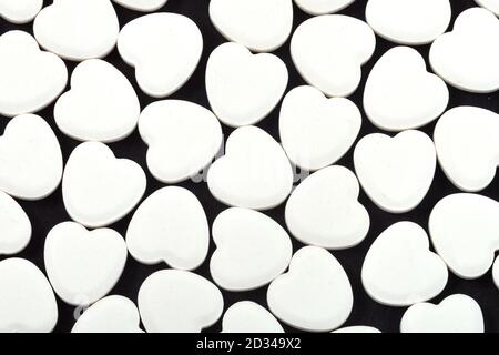 Herzförmige Pillen auf schwarzem Hintergrund. Medikamente, die Menschen helfen. Stockfoto