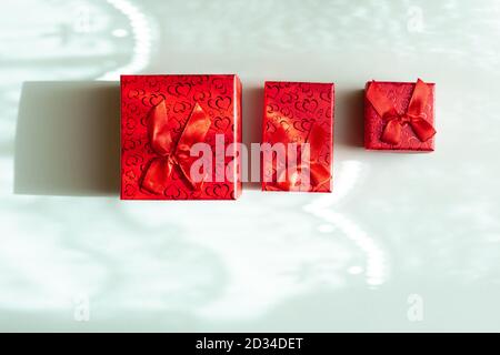 Drei rote Geschenkschachteln in verschiedenen Größen isoliert auf blau Hintergrund Stockfoto