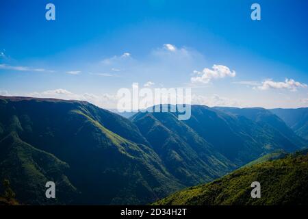 Natürlicher Blick auf die gefalteten Berge und üppig grüne Täler mit klarem Himmel und Wolken von Cherrapunji, Meghalaya, Nordostindien Stockfoto