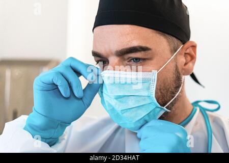 Nahaufnahme Porträt mit Gesicht eines jungen Chirurgen Arzt Tragen medizinische Maske - Fokus auf das Auge des Mannes Stockfoto