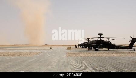 Ein Staubteufel fegt vorbei geparkten britischen AH-64 Apache Attack Helicopters in Camp Bastion, Provinz Helmand, Afghanistan. Stockfoto