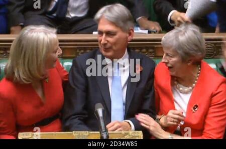 Finanzminister Liz Truss (links) und Premierministerin Theresa May gratulieren dem Schatzkanzler Philip Hammond zum Abschluss seiner Haushaltserklärung an die Abgeordneten im Londoner Unterhaus. Stockfoto