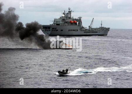 Ein Boot, das bis zu fünf Tonnen Kokain mit einem geschätzten Straßenwert von Â£500 Millionen transportiert, brennt in der Karibik, nachdem es nach einer Nachtschicht vom Royal Fleet Auxiliary Ship RFA Wave Ruler (Hintergrund) gefangen wurde. Stockfoto