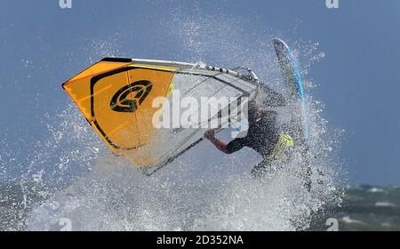 Ein Windsurfer stürzt durch die Wellen bei windigen Bedingungen im Camber, East Sussex. Stockfoto