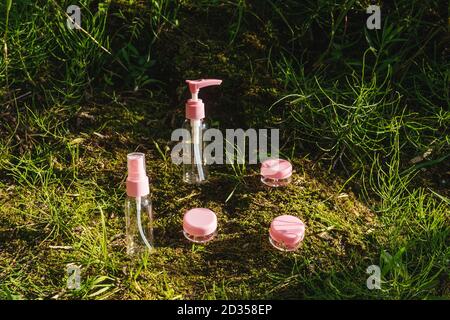 Flache Lay-Zusammensetzung mit rosa Glasflaschen der Körperpflege Bio-Kosmetik mit Öl auf natürlichen Hintergrund Moos und Gras. Stockfoto