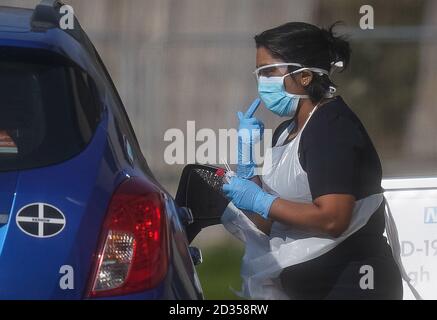 Ein NHS-Mitarbeiter, der auf Coronavirus bei einer temporären Fahrt durch die Teststation im Parkplatz von Chessington World of Adventures in Chessington, Greater London, getestet wird. Stockfoto