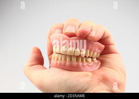 Zahnprothese in der menschlichen Hand isoliert auf der weißen Hintergrund Stockfoto