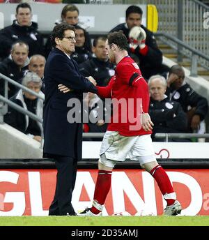 England-Manager Fabio Capello schüttelt Wayne Rooney nach seiner Substitution beim Internationalen Freundschaftsspiel im Wembley Stadium, London, die Hände. Stockfoto