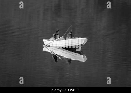ULSTEINVIK, NORWEGEN - 2019. JUNI. Zwei Menschen von hinten fischen von einem kleinen Boot im Fjord in Norwegen Stockfoto