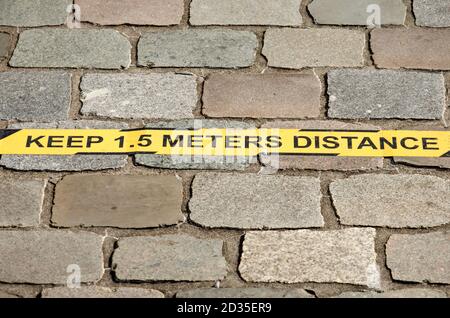 Delft, Niederlande, 4. Oktober 2020: Gelbe Streifen auf dem Bürgersteig auf dem Universitätscampus mit Ratschlägen, 1.5 Meter Abstand zu halten, um zu preven Stockfoto