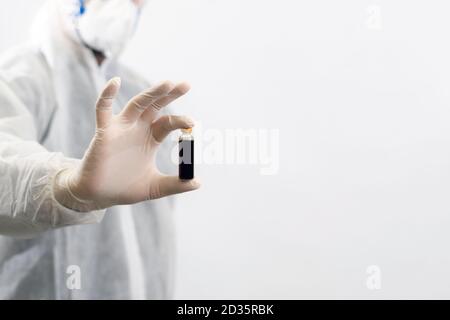 Wissenschaftler mit einer Maske, die eine Flasche Impfstoff für Corona-Virus hält. Covid-19 Gegengift. Doktor entdeckt Behandlung für epidemische Krankheit. Global Stockfoto