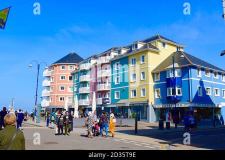 Eine bunte Mischung aus modernen Gebäuden, die Wohnungen/Wohnungen über Geschäften bieten. Einige Wohnungen haben Balkon mit Blick auf das Meer. Stockfoto