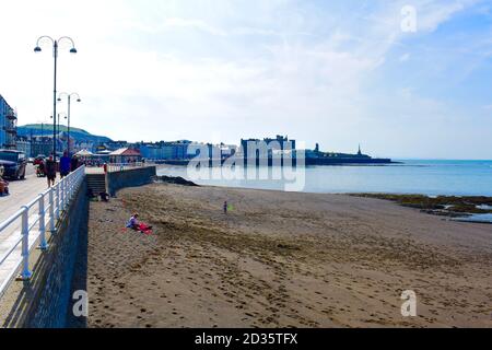 Blick von der Marine Terrace auf den Royal Pier im Badeort Aberystwyth. Menschen, die gerne an der Promenade in der Sonne spazieren Stockfoto