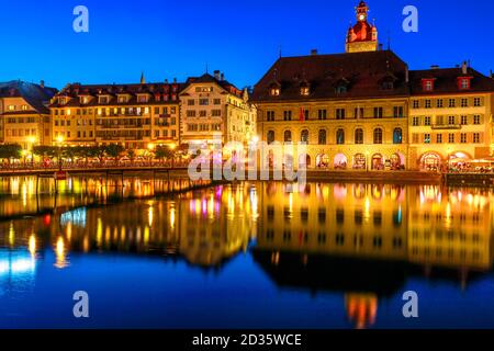Mittelalterliche Stadt Luzern am Ufer des Vierwaldstatersees, beleuchtet bei Nacht. Kornschutte oder Rathaus und Gebäude spiegeln sich in Ruhe Stockfoto