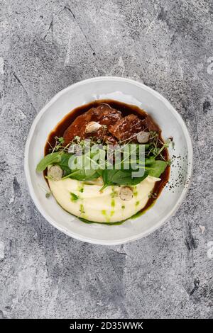 Kalbsbacken in Soße mit Kartoffeln und Kohl, mit Kräutern verziert Stockfoto