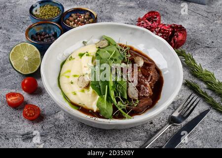 Kalbsbacken in Soße mit Kartoffeln und Kohl, mit Kräutern verziert Stockfoto
