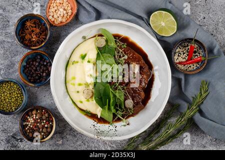 Kalbsbacken in Soße mit Kartoffeln und Kohl, mit Kräutern verziert Stockfoto