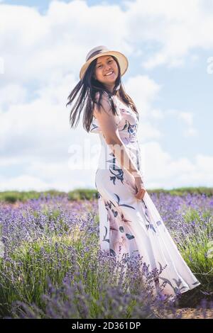 Portrait von schönen romantischen Frau Blumenkleid und stilvollen Hut Im Bereich der Lavendelblüten Stockfoto