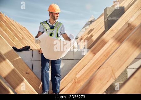 Zufriedener Baustellenmitarbeiter prüft die Blaupause eines Gebäudes Stockfoto