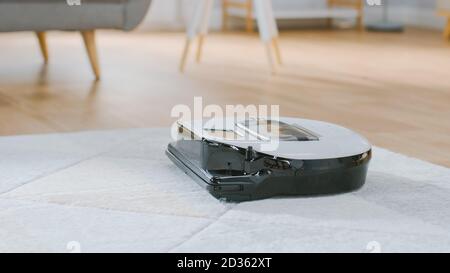 Nahaufnahme eines intelligenten Roboter-Staubsaugers, der Staub von einem Teppich saugt. Das Gerät Für Technologische Haushaltsgeräte Geht An Ihnen Vorbei. Stockfoto