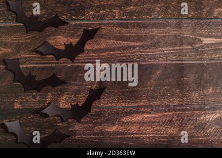 Schwarze Papier Fledermaus Silhouetten auf braunem Holzhintergrund, Halloween-Konzept, Draufsicht, Platz für Text, Flat Lay für dein Design Stockfoto