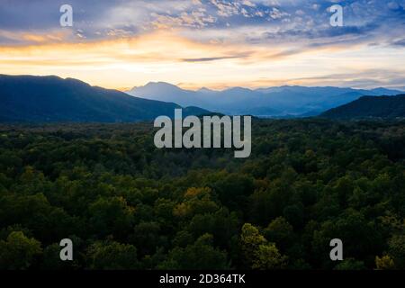 Panoramablick auf die Berge bei Sonnenuntergang mit einem Wald im Vordergrund, Freiheit und Abenteuer Reisekonzept Stockfoto