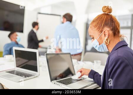 Geschäftsfrau mit Gesichtsmaske Desinfektion Laptop wegen Covid-19 Stockfoto