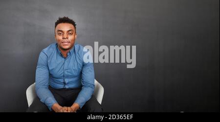 Junge afrikanische Student oder Geschäftsmann sitzen entspannt in einem Stuhl Stockfoto