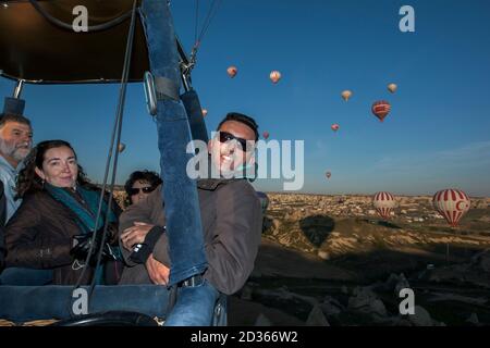 Passagiere an Bord eines Heißluftballons genießen bei Sonnenaufgang die wunderschöne Landschaft oberhalb von Goreme in der Region Kappadokien in der Türkei. Stockfoto