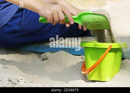 Das Kind spielt in der warmen Jahreszeit auf dem Spielplatz. Das Kind gräbt im Sandkasten der Kinder. Stockfoto