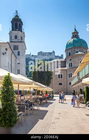 Menschen sitzen an einem sonnigen Sommernachmittag in einem Café vor dem Salzburger Dom (Dom zu Salzburg). Stockfoto