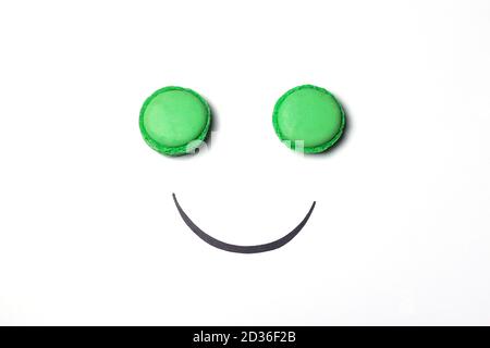 Smiley Face Konzept. Smiley-Gesicht aus Makronen auf weißem Hintergrund. Sweet Smiley Face Metapher. Stockfoto