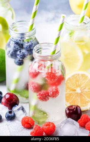 Beere und Zitrusfrüchte infundiert Sommer kalte Getränke in Glasflaschen auf grauen Stein Tisch Hintergrund, kopieren Raum Stockfoto