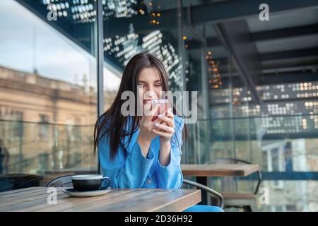 Nahaufnahme Porträt glücklich lächelnde Frau Blick auf Telefon mit positiv Leichtes Lächeln im Gesicht sehen lustige News-Fotos auf ihr Home Balkon oder auf einem Kaffee s Stockfoto