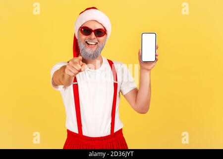 Extrem glücklich fröhlich grau bärtigen Mann im weihnachtsmann Kostüm zeigt Finger auf Kamera Smartphone mit leerem Display, Urlaub Boni. Zoll Stockfoto