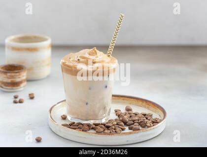 Dalgona Kaffee mit süßem Schaum und Eis in einem Glas mit Stroh. Schlagkaffee. Grauer Hintergrund. Horizontales Bild. Platz für Text. Stockfoto