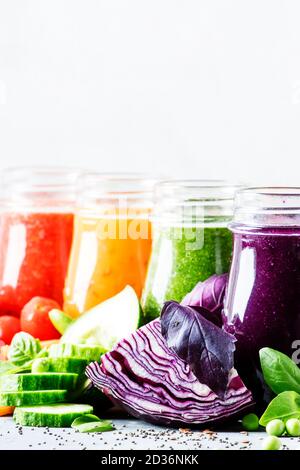 Bunte vegane Gemüsesäfte und Smoothies in Glasflaschen auf grauem Tisch, selektiver Fokus Stockfoto