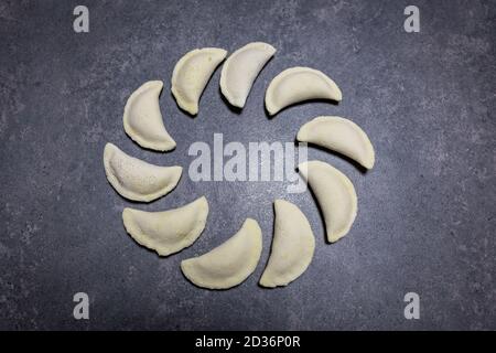 Polnische glutenfreie Knödel (Pierogi), polnisches Nationalgericht aus Teig und herzhafter oder süßer Füllung. Mehrere gefrorene Knödel liegen auf einem Tisch. Stockfoto