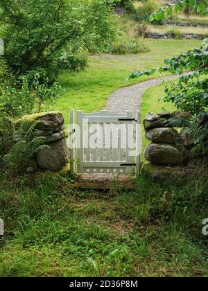 Eingang zum grünen Garten mit weißem Tor Stockfoto