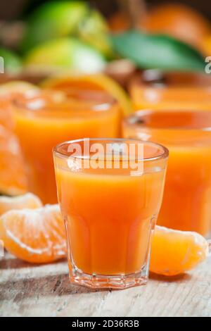 Frischer Mandarinensaft mit Mandarinscheiben auf altem Holzhintergrund, selektiver Fokus Stockfoto