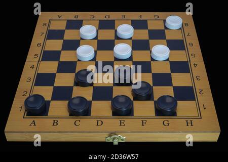 Checkers Brettspiel. Brett mit Steinen isolieren auf einem schwarzen Hintergrund Nahaufnahme. Stockfoto