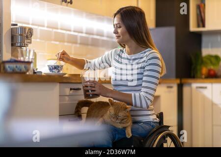 Frau im Rollstuhl in der Küche zu Hause Stockfoto